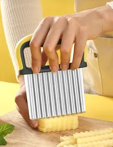 Close-up of stainless steel wavy potato cutter slicing through potato on wooden board