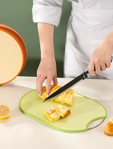 Professional chef slicing fresh bread on a green non-slip plastic cutting board