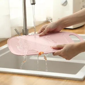 Eco-friendly pink wheat straw cutting board being washed in a modern kitchen sink
