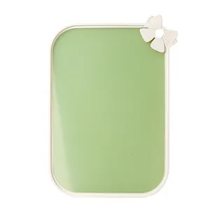 Double-sided light green cutting board with white bow detail on white background