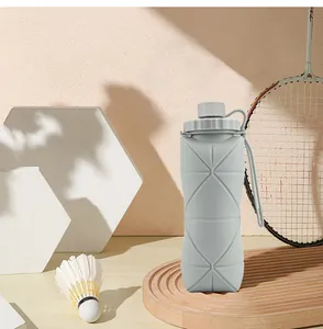 Grijze opvouwbare siliconen waterfles met badmintonracket en shuttle op een dienblad