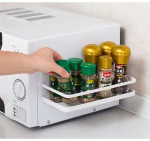Detailed view of white magnetic side rack holding spice jars on a kitchen microwave.