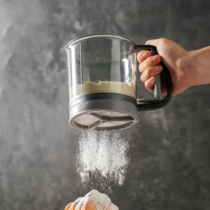 Handheld semi-automatic flour sifter tool sifting white sugar onto a fresh croissant pastry