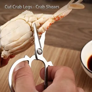 Durable stainless steel crab scissors effectively cutting a thick crab leg in a kitchen setting