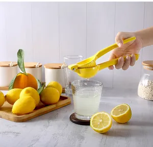 Detail showing a yellow manual lemon squeezer pressing fresh fruit into a glass cup
