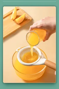 Detail shot of a fine mesh strainer filtering fresh orange juice into a glass bowl.