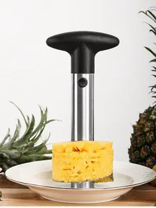 Close-up of a stainless steel pineapple corer lifting a fresh fruit slice onto a plate