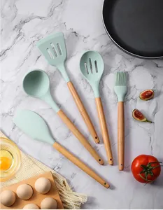 Gros plan d'ustensiles de cuisine en silicone vert menthe avec manches en bois