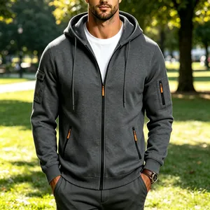 Detail van grijze techwear hoodie met oranje ritsaccenten en handige zakken voor mannen