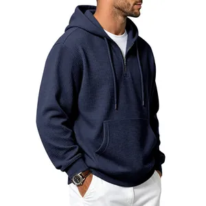 Detailed view of navy blue waffle-knit hoodie featuring a half-zip and front pocket