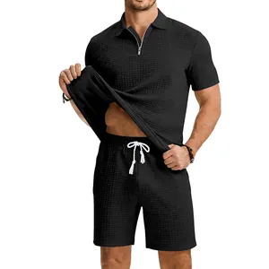 Détail d'un ensemble deux pièces noir pour homme en maille gaufrée avec polo et short.