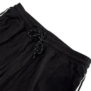 Close-up detail showing the elastic waistband and speckled drawstring of black corduroy pants