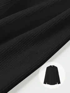 Close-up macro detail of black waffle texture fabric on a long sleeve men's polo shirt.