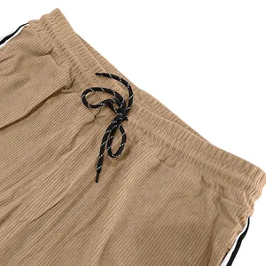 Close-up detail of the elastic waistband and drawstring on brown corduroy pants.