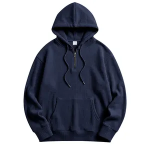 Detailed view of navy blue waffle knit hoodie featuring a half-zip and kangaroo pocket.