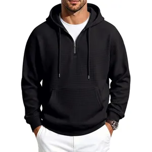 Close-up of men's black waffle knit hoodie with half-zip design and kangaroo pocket