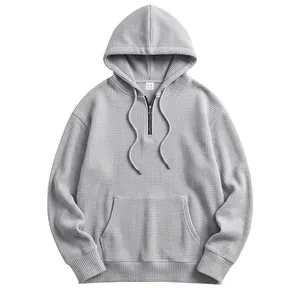 Detailed view of light gray waffle-knit half-zip hoodie featuring a kangaroo pocket and drawstring