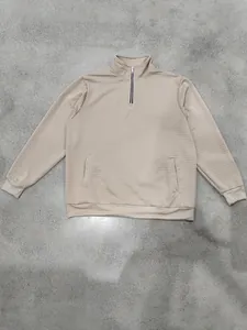 Detalle de sudadera jacquard de cuadros con media cremallera y cuello alto en beige