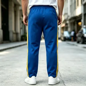 Back view of blue men's sports joggers with yellow side stripes on a city street