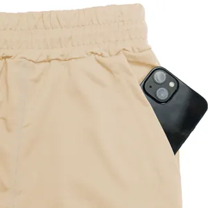 Close-up view of beige athletic shorts showing a functional side pocket with a smartphone