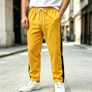 Close-up detail of men's yellow sweatpants with black side stripes and drawstring waist