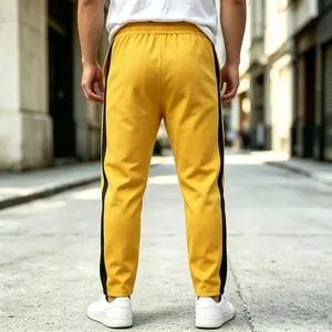 Rear view of yellow men's sweatpants featuring bold black side stripes in urban street
