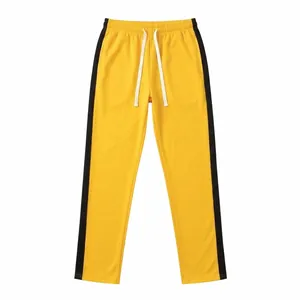 Yellow sports sweatpants with black side stripes and white adjustable drawstring.