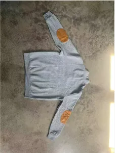 Dettaglio di una felpa da uomo in maglia a nido d'ape grigia con toppe marroni sui gomiti
