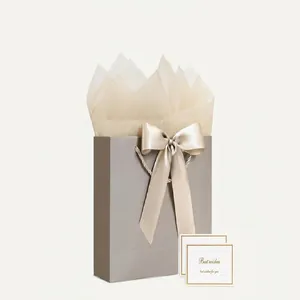 Close-up of grey gift bag with champagne bow, tissue paper, and greeting cards.