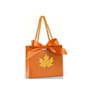 Detailed macro view of an orange wedding gift box featuring a ribbon and golden leaf