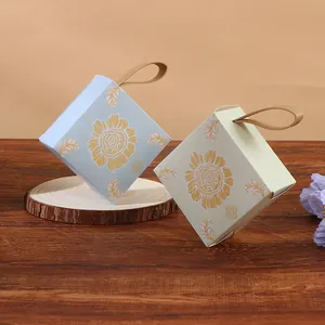 Close-up view of elegant square candy boxes with gold sunflower patterns and handles