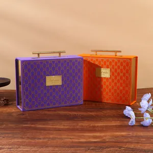 Elegant purple and orange wedding candy gift boxes with gold handles on a wooden table