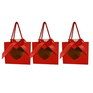 Set of three vibrant red paper gift bags with a heart-shaped window and satin ribbon bow