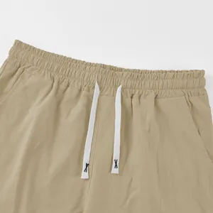 Macro detail of men's beige linen shorts featuring elastic waist and white drawstring.