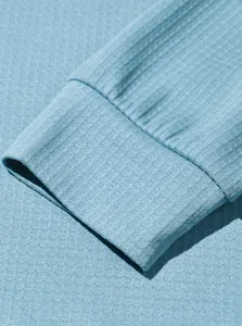 Primer plano de la tela de nido de abeja azul claro y el detalle del puño de un polo.