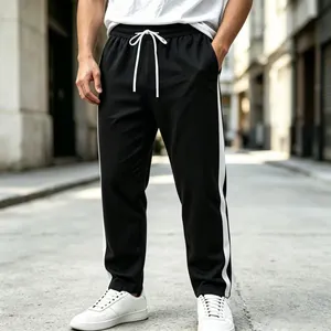 Close-up of men's black sports sweatpants featuring white side stripes and drawstring