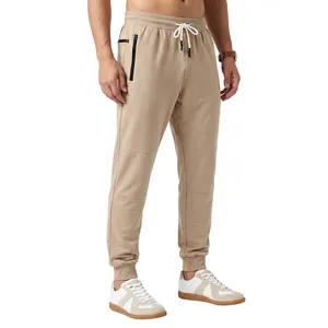 Detailed view of men's beige joggers featuring a drawstring waist and side zipper pockets