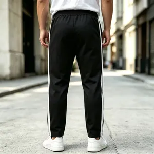 Rear view of black straight sweatpants with white side stripes for men in casual street style