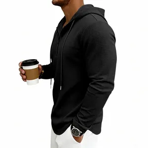 Dettaglio ravvicinato della felpa con cappuccio nera in maglia a nido d'ape con mezza zip.