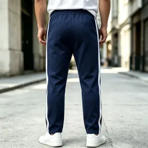 Back view of men's navy blue athletic sweatpants with white side stripes in street setting