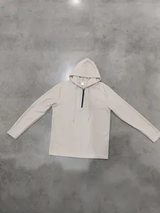 Dettaglio della trama a nido d'ape beige sulla felpa con cappuccio e mezza zip.