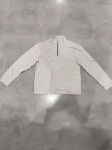 Close-up detail of a beige vertical ribbed half-zip sweatshirt featuring a mock neck collar