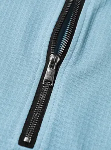 Detalle del cierre metálico plateado en un polo de punto gofre azul claro para hombre