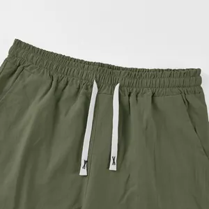 Close-up of olive green linen shorts featuring elastic waistband and white drawstring