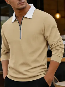 Detalle de polo de punto gofrado caqui con cremallera y cuello blanco en contraste.