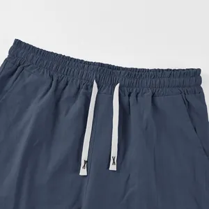 Detail view of navy blue men's linen shorts featuring elastic waistband and white drawstrings