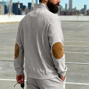 Detailweergave van grijze corduroy heren sweater met halve rits en bruine elleboogstukken
