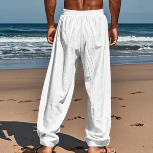 Back view of men's loose white linen trousers shown in a sunny beach vacation setting