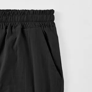Close-up of black men's linen shorts showing elastic waistband and pocket detail