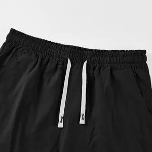 Close-up detail of black linen shorts featuring an elastic waistband and white drawstring